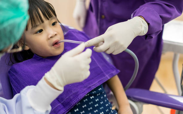 istock Dentist and assistant checking and cleaning Asian girls teeth using suction machine in the dentists chair. 839584374