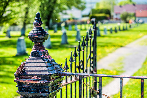 Cemetery and gravestones in summer with vintage metal railing gate fence