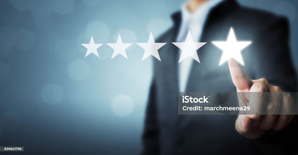 Uomo d'affari punta il simbolo a cinque stelle per aumentare il rating dell'azienda - Foto stock royalty-free di Misurare