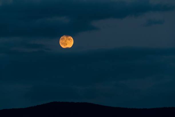 istock Full moon rising over silhouetted mountains among clouds 839687214
