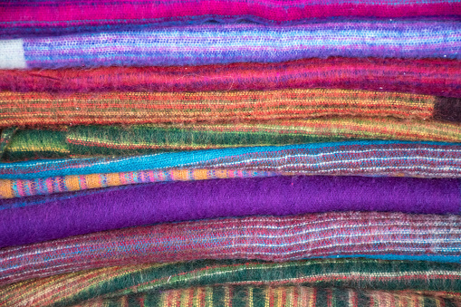 Brightly coloured Asian woven scarves in pile.