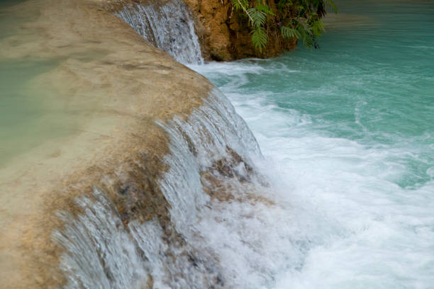 A selfie taken on a mobile phone of a mature female tourist taking a picture at a local beauty spot in Luang Prabang in Laos in southeast Asia the waterfall she is visiting is called Kuang Si Waterfall. She is admiring the beauty and strength in nature and taking selfies for her memories.