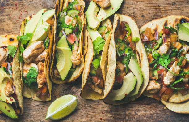 Tacos with grilled chicken, avocado, fresh salsa sauce and limes