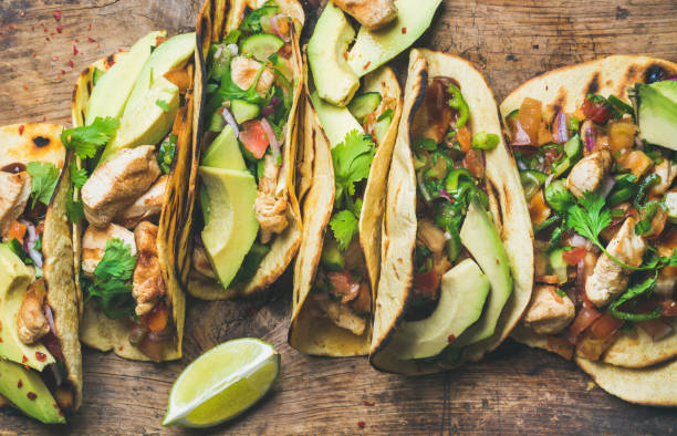 Tacos with grilled chicken, avocado, fresh salsa sauce and limes Tacos with grilled chicken, avocado, fresh salsa sauce and limes over rustic wooden background, top view. Healthy low carb and low fat lunch or food for company. Dieting and weight loss concept foxys_forest_manufacture stock pictures, royalty-free photos & images