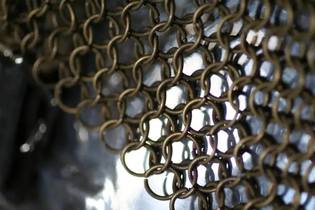 A close up shot of brass colored chainmail armor on a silver breastplate
