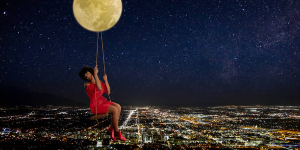 Woman in swing hanging from moon over Sat Lake City