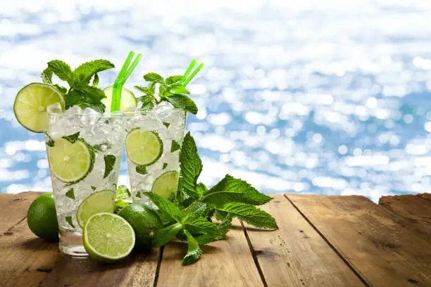 Photo of Two mojito cubano drinks against defocused shiny sea water