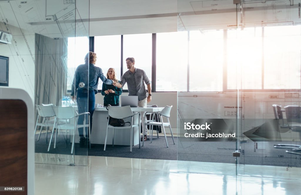 Businesspeople shaking hands after successful meeting Businesspeople shaking hands after meeting in board room. Businessman shaking hands with female in conference room at office. Customer Stock Photo