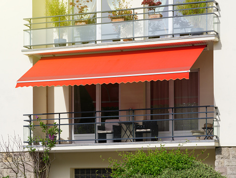 French balcony with awning opened covered by sun-shield on a warm summer day