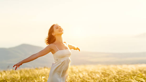 幸せ自然円周の夕日に背を向けて立っている女性は、手を開く - enjoyment ストックフォトと画像