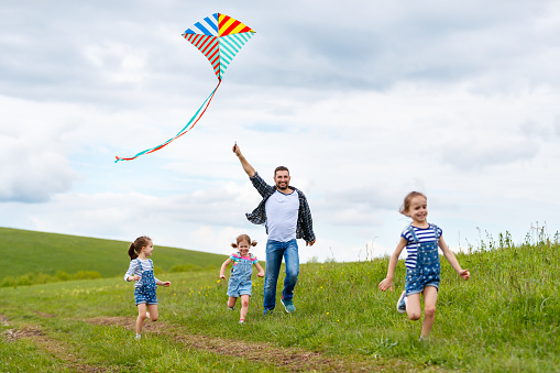 happy family father and children run with a kite on summer meadow