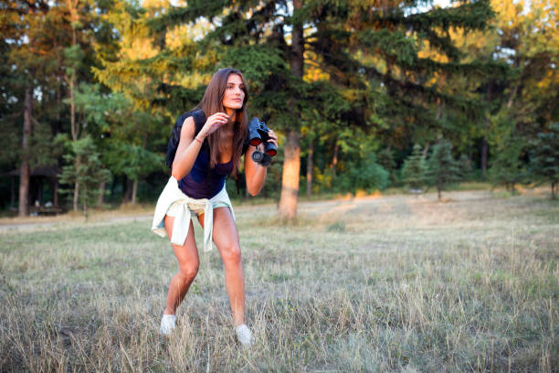 Young woman using binoculars in natureYoung woman exploring the nature, holding binoculars