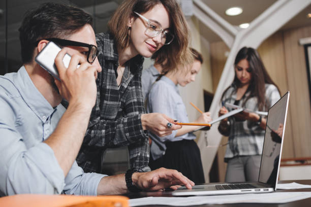 istock Teamwork concept. Coworking people work together in loft office. Bearded businessman talks on smartphone. Female manager holding presentation on laptop 839863736
