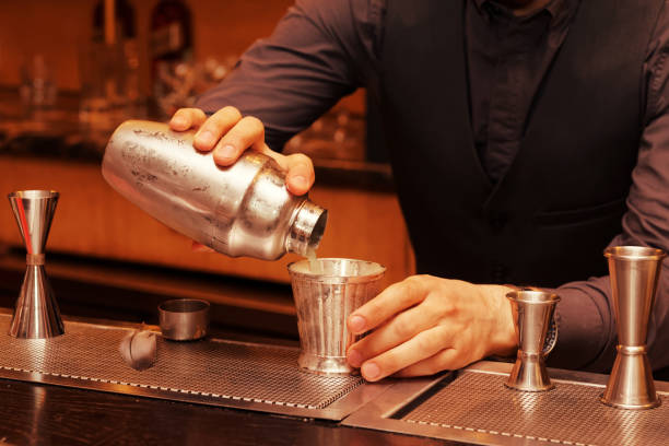 istock Bartender is pouring cocktail into a glass, toned 839867738