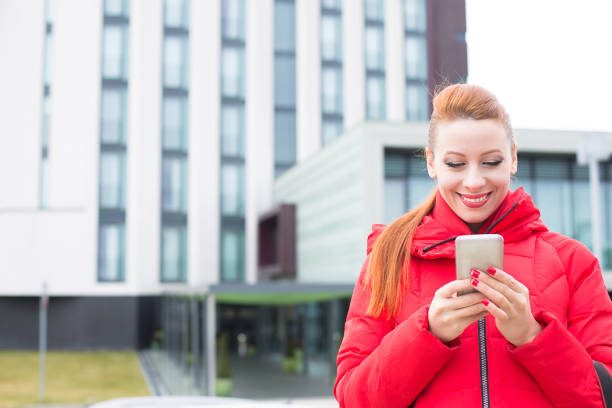 istock Happy woman using texting on smart phone outdoors on a city modern building background 839871252