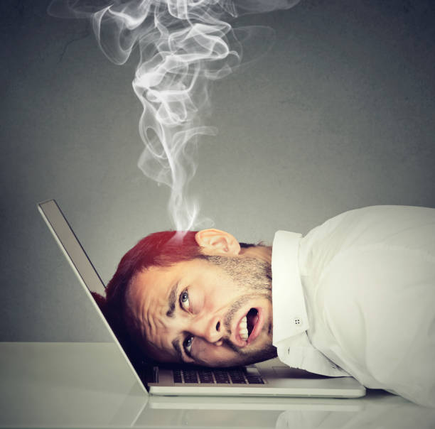 Stressed employee man with overheated brain using laptop