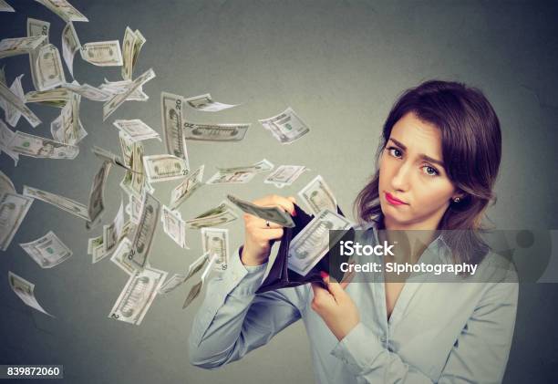 Sad Woman Showing Her Wallet With Money Dollar Banknotes Flying Out Away Stock Photo - Download Image Now