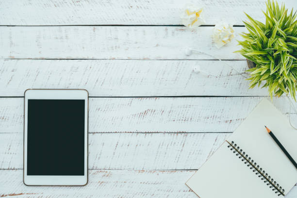 istock Digital tablet and note book on white wooden table blank space. 839878720