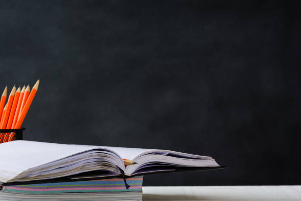 istock book and pencil on white table black board background 839879192