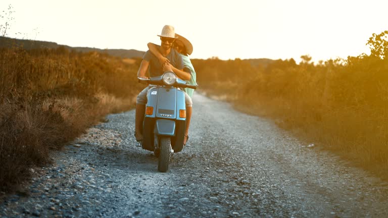 Couple on a scooter riding through a countryside.