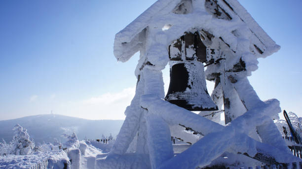 thick snow-covered Peace Bell on the Fichtelberg in the Ore Mountains in Saxony, Germany, in the background of Klinovec in the Bohemian part of the Ore Mountains, winter wonderland