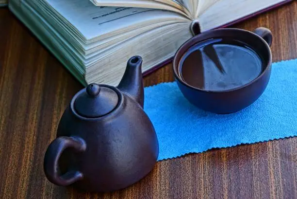 tea utensils with a drink on a table near a thick open book