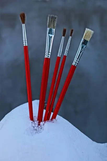 thin red paintbrushes for painting in a snowdrift on a gray background
