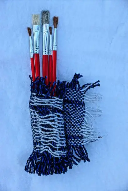 red tassels wrapped in a piece of cloth made of wool on white snow