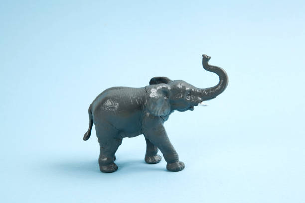 pop elephant figurine a plastic elephant on a vibrant blue background. Minimal color still life photography elephant figurine stock pictures, royalty-free photos & images