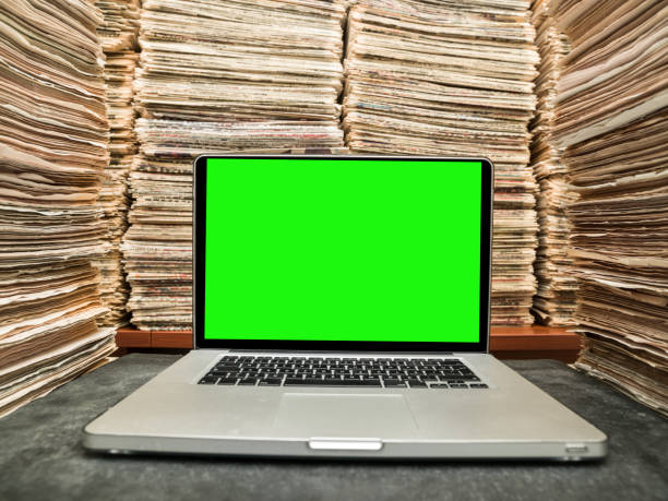 laptop on desk in printed media library - book stack embracing business imagens e fotografias de stock