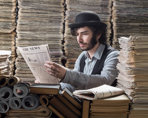 young man in old fashioned clothes doing research in printed media library - young adult reading newspaper the media imagens e fotografias de stock