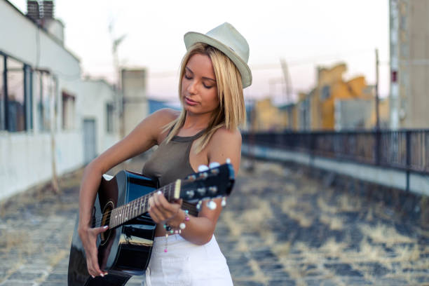 Young woman playing acoustic guitar on sunny day near the river