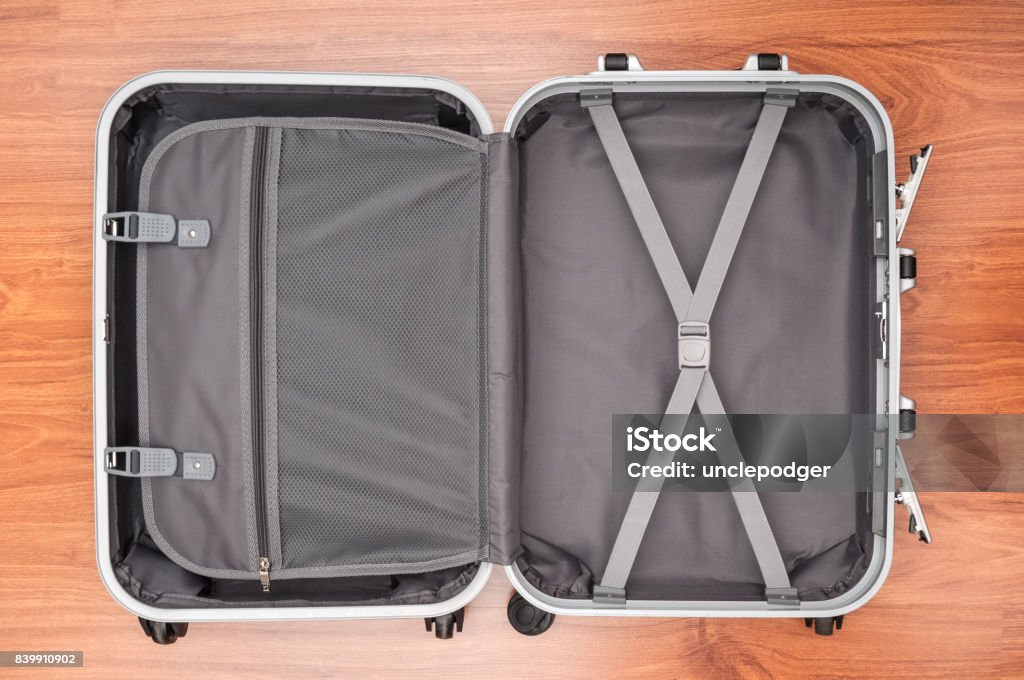 Opened empty travel bag on wooden floor Suitcase Stock Photo