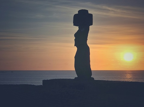 Ahu Tahai Moai statue silhouette at the coast of Hanga Roa during a beautiful sunset. Hanga Roa, Rapa Nui, Easter Island, Chile.