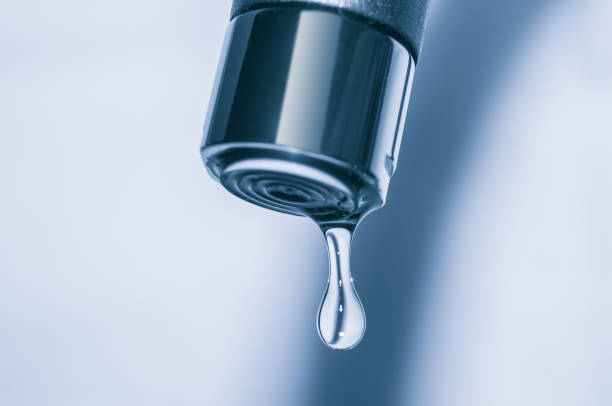 istock Faucet and water drop close up on blue background 839935628