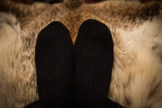 istock Warm hand knitted woolen socks on a fur background. First person view. 839938944