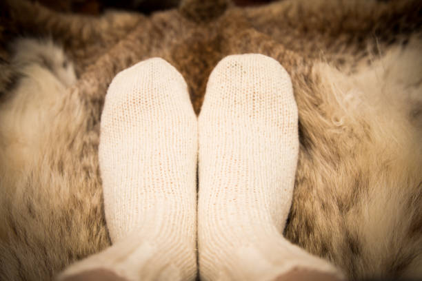 istock Warm hand knitted woolen socks on a fur background. First person view. 839938952