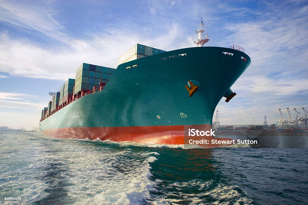 Com vista para a proa do navio carregado de carga, saindo do porto. - Foto de stock de Navio cargueiro royalty-free