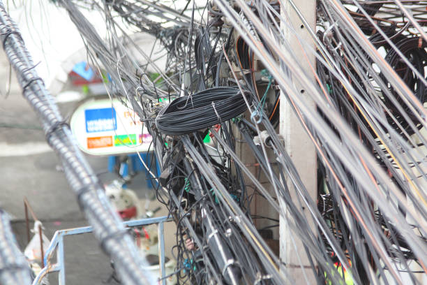 Messy cables attached to electrics pole including electrics, phone and others communication cables