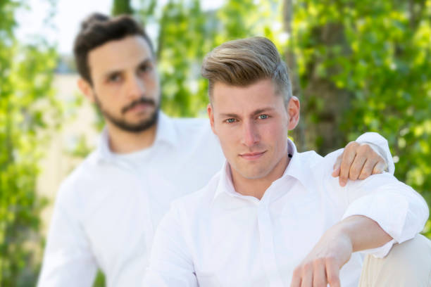istock two young man in white shirts sitting outside 839945030