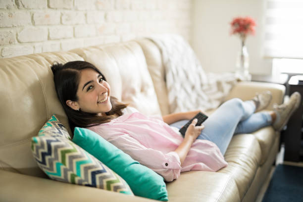 istock Beautiful young woman watching television 839949528
