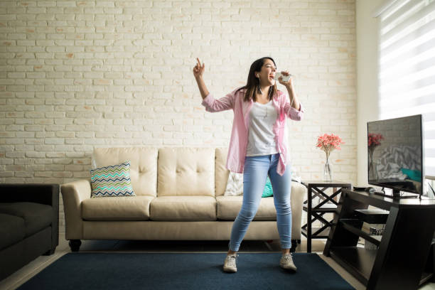 singing in the living room - young adult technology beautiful singing imagens e fotografias de stock