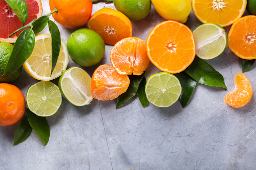 Healthy food, diet, nutrition, nature concept. Citrus fruits vitamin background. Orange, grapefruit, tangerine, lime, lemon with leaves on a grunge black table. Top view flat lay overhead