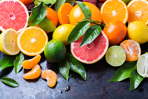 Healthy food, diet, nutrition, nature concept. Citrus fruits vitamin background. Orange, grapefruit, tangerine, lime, lemon with leaves on a grunge black table