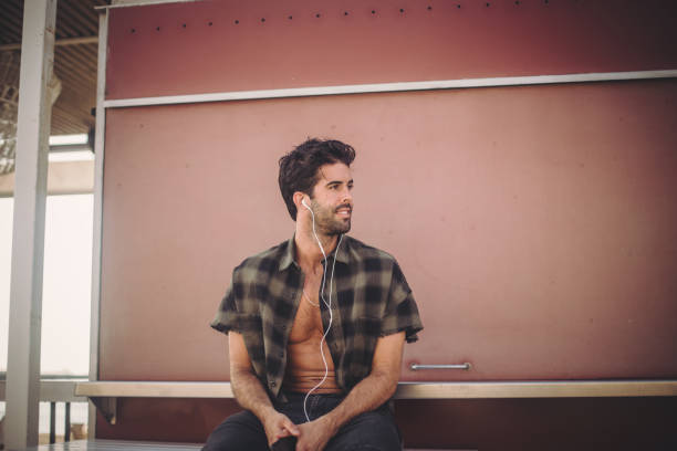 hombre con auriculares sentado al aire libre - fully unbuttoned audio fotografías e imágenes de stock