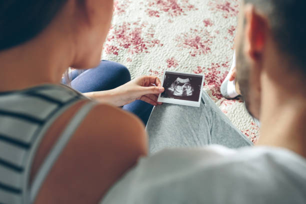 Couple looking at ultrasound of their baby Couple looking at ultrasound of their baby sitting on the bed. Selective background focus on ultrasound medical scanner photos stock pictures, royalty-free photos & images