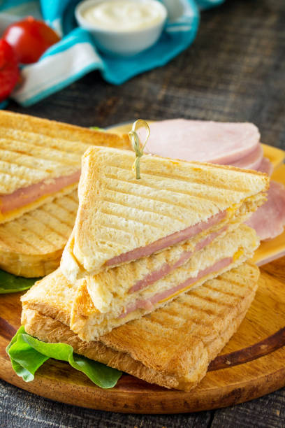 istock Pressed and toasted double sandwich with ham and cheese, served with lettuce leaves on a kitchen wooden table. 840044548
