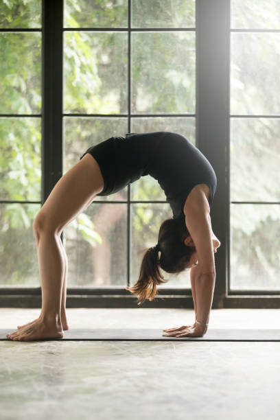 istock Young attractive woman in Urdhva Dhanurasana pose, studio background 840048072