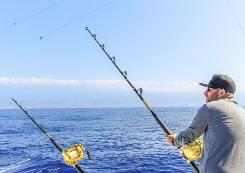 Man and a fishing rod looking out at the ocean, deep sea fishing