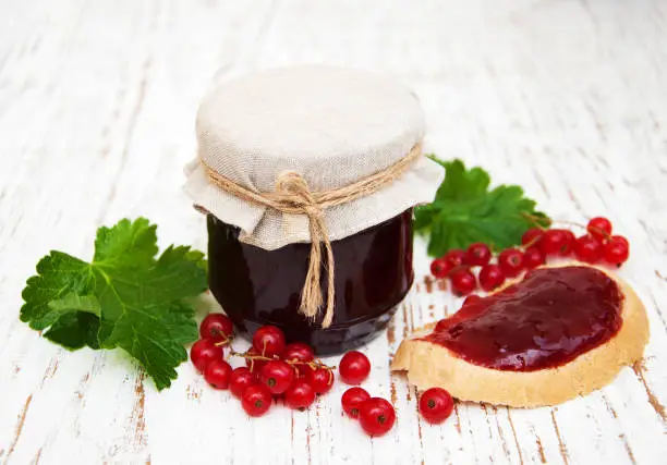 Redcurrants jam with fresh berries on a wooden background